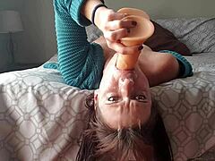 Kleine zelfgemaakte video van volwassen vrouw die kokhalst op dildo ondersteboven